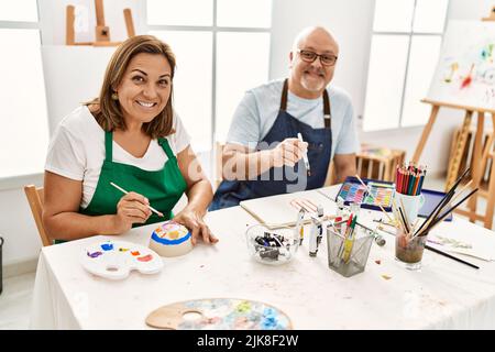 Le peintre hispanique d'âge moyen couple souriant Happy Painting au studio d'art. Banque D'Images