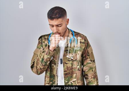 Jeune médecin hispanique portant camouflage uniforme de l'armée se sentant mal et toussant comme symptôme de rhume ou de bronchite. Concept de soins de santé. Banque D'Images