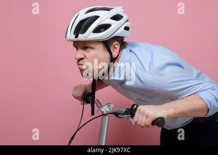 Homme caucasien confus portant sur le vélo sur fond coloré Banque D'Images