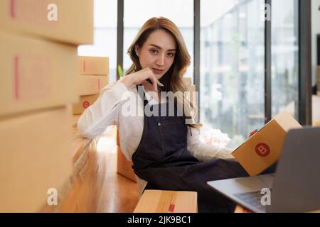 Jeune femme asiatique à l'entrepôt à la livraison à l'entrepreneur propriétaire PME. Entreprise numérique en ligne PME petite entreprise et boutique en ligne. Banque D'Images