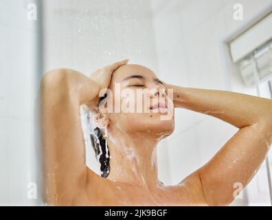 Relâchez le stress avec une bonne douche. Une jeune femme lavant ses cheveux avec du shampooing dans la douche à la maison. Banque D'Images