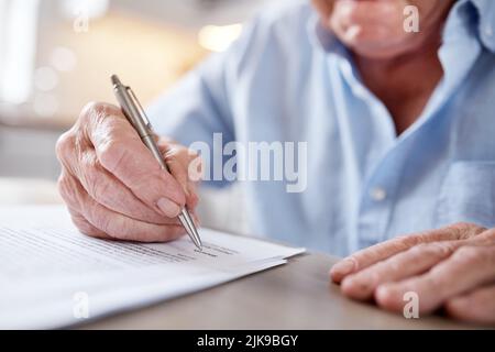 Ainsi, vous n'aurez jamais à vous demander comment ou pourquoi. Un homme méconnaissable remplissant des formes à la table de cuisine à la maison. Banque D'Images