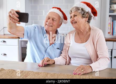 Souvenez-vous de moi... un couple âgé qui prend un selfie festif à la maison. Banque D'Images