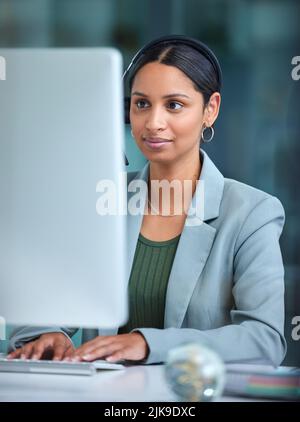 Notre équipe travaille sur ce sujet : une femme d'affaires utilisant un ordinateur tout en travaillant dans un centre d'appels. Banque D'Images