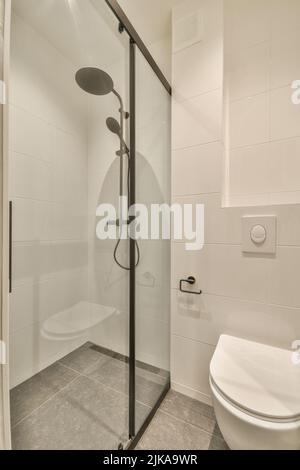 Design intérieur élégant de la salle de bains avec toilettes blanches et cabine de douche avec douche en verre dans un appartement moderne Banque D'Images