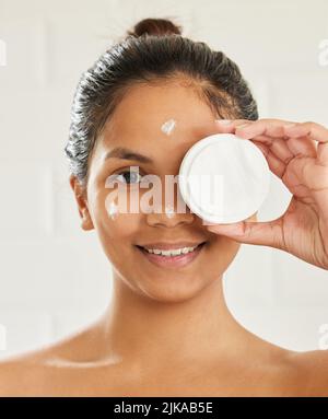 La beauté est un voyage profondément personnel. Jeune femme posant avec hydratant facial à la maison. Banque D'Images