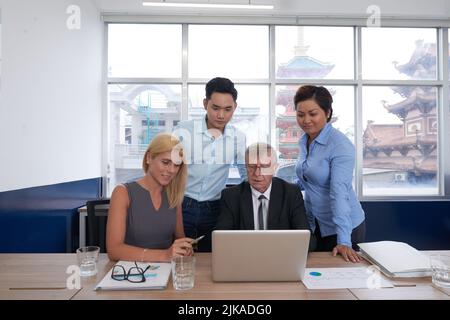 L'équipe internationale d'affaires se réunissait sur un ordinateur portable avec présentation Banque D'Images