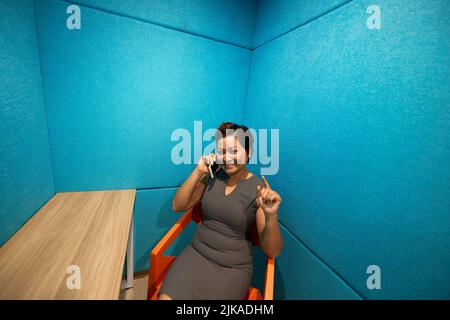 Jeune femme souriante parlant au téléphone dans la salle de négociation Banque D'Images