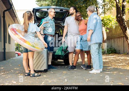 Famille et amis divers voyageant en vacances en bord de mer, en voiture avec bagages et valises. Enfant, parents et grands-parents qui partent en vacances d'été avec bagages et gonflables. Banque D'Images