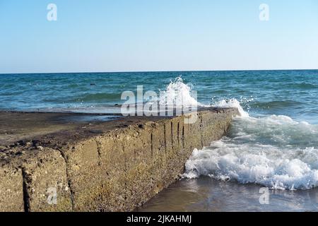 Les vagues frappent des blocs de béton en mer en été Banque D'Images