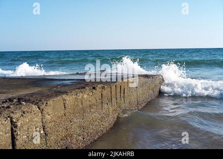 Les vagues frappent des blocs de béton en mer en été Banque D'Images