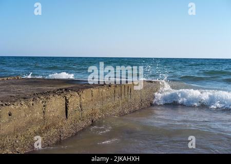 Les vagues frappent des blocs de béton en mer en été Banque D'Images