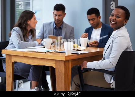 Le travail d'équipe est la capacité de travailler ensemble. Un groupe de collègues ayant une réunion et un petit déjeuner dans un bureau moderne. Banque D'Images