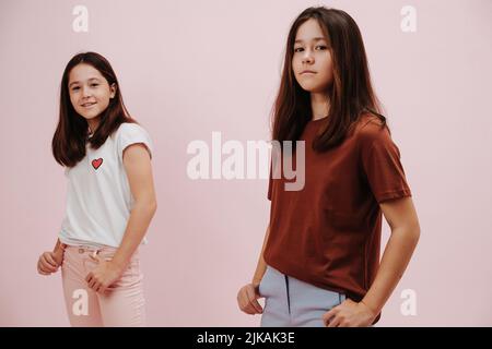 Portrait de deux filles jumelles confiantes vêtues de différentes couleurs posant Banque D'Images