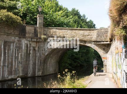 Cycliste longeant le chemin de halage du canal Leeds Liverpool à Armley Mills, Leeds, Yorkshire, Angleterre, Royaume-Uni Banque D'Images