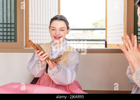 Des filles coréennes et caucasiennes portant Hanbok jouant à Yut, jeu de société traditionnel coréen Banque D'Images