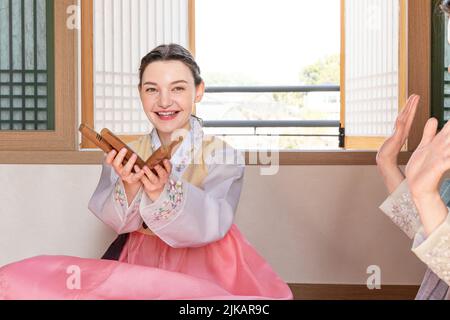 Des filles coréennes et caucasiennes portant Hanbok jouant à Yut, jeu de société traditionnel coréen Banque D'Images