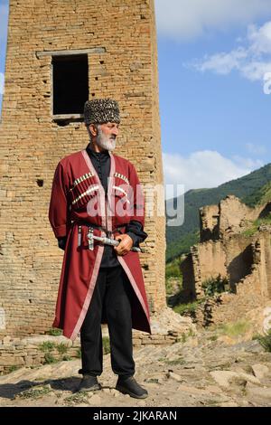Dagestan, Russie - 21 juillet, 2022: Homme local dans la tradition nationale robe reste contre tour de bataille dans le village de Goor Banque D'Images