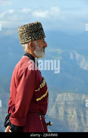 Dagestan, Russie - 21 juillet, 2022: Homme local dans la tradition nationale robe debout en profil contre les montagnes caucasiennes dans le village de Goor Banque D'Images