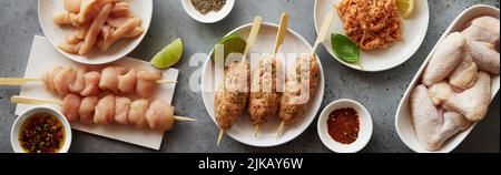 Vue de dessus tas de viande de poulet crue placé sur fond gris avec des épices et des limes dans la cuisine légère à la maison Banque D'Images