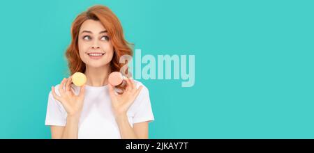 bonne fille tient doux macaron cookie français sur fond bleu. Femme isolé visage portrait, bannière avec maquette d'espace de copie. Banque D'Images