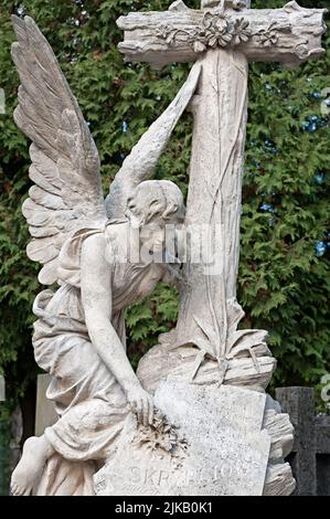 Sculpture tombeau d'un ange mettant une fleur sur une pierre tombale au cimetière de Lychakiv à Lviv, Ukraine Banque D'Images