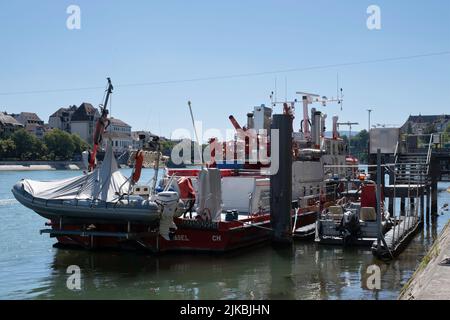 Feu rouge et blanc ('Feuerlöschboot') avec des bateaux de sauvetage en caoutchouc plus petits amarrés sur le quai du Rhin dans la ville de Bâle par une journée ensoleillée en été Banque D'Images