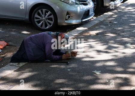 Le mendiant féminin avec un foulard supplie d'argent de s'agenouiller sur un trottoir entre les voitures garées à Rome. Scène de la crise sociale, économico-politique moderne Banque D'Images