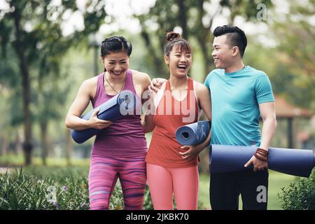 Rire de jeunes femmes vietnamiennes sportives avec des tapis de yoga Banque D'Images