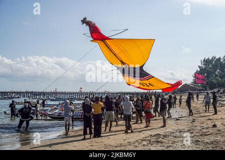 Denpasar, Indonésie. 31st juillet 2022. Les participants attrapent leur cerf-volant lors de leur atterrissage. Des milliers de personnes affluent à Mertasari Beach à Sanur pour un festival de cerf-volant pendant la saison de cerf-volant de Bali, qui s'étend de mai à septembre chaque année, entre la saison sèche. Le festival est le meilleur moment de l'année pour visiter Bali. Les couleurs rouge, blanc, noir et jaune-or représentent les incarnations des divinités hindoues balinaises. Crédit : SOPA Images Limited/Alamy Live News Banque D'Images