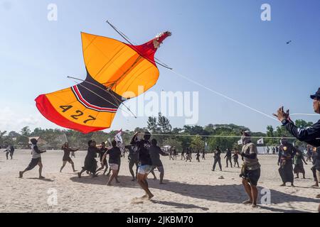 Denpasar, Indonésie. 31st juillet 2022. Les participants attrapent leur cerf-volant lors de leur atterrissage. Des milliers de personnes affluent à Mertasari Beach à Sanur pour un festival de cerf-volant pendant la saison de cerf-volant de Bali, qui s'étend de mai à septembre chaque année, entre la saison sèche. Le festival est le meilleur moment de l'année pour visiter Bali. Les couleurs rouge, blanc, noir et jaune-or représentent les incarnations des divinités hindoues balinaises. Crédit : SOPA Images Limited/Alamy Live News Banque D'Images