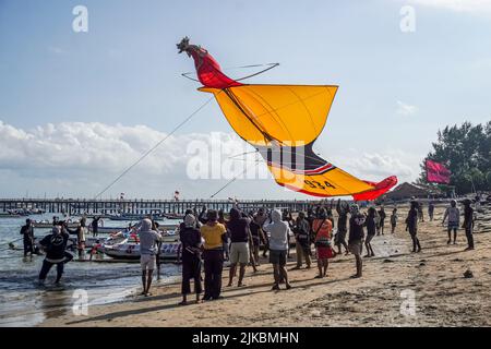 Denpasar, Indonésie. 31st juillet 2022. Les participants attrapent leur cerf-volant lors de leur atterrissage. Des milliers de personnes affluent à Mertasari Beach à Sanur pour un festival de cerf-volant pendant la saison de cerf-volant de Bali, qui s'étend de mai à septembre chaque année, entre la saison sèche. Le festival est le meilleur moment de l'année pour visiter Bali. Les couleurs rouge, blanc, noir et jaune-or représentent les incarnations des divinités hindoues balinaises. (Photo de Dicky Bisinglasi/SOPA Images/Sipa USA) crédit: SIPA USA/Alay Live News Banque D'Images