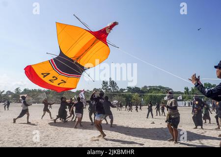 Denpasar, Indonésie. 31st juillet 2022. Les participants attrapent leur cerf-volant lors de leur atterrissage. Des milliers de personnes affluent à Mertasari Beach à Sanur pour un festival de cerf-volant pendant la saison de cerf-volant de Bali, qui s'étend de mai à septembre chaque année, entre la saison sèche. Le festival est le meilleur moment de l'année pour visiter Bali. Les couleurs rouge, blanc, noir et jaune-or représentent les incarnations des divinités hindoues balinaises. (Photo de Dicky Bisinglasi/SOPA Images/Sipa USA) crédit: SIPA USA/Alay Live News Banque D'Images