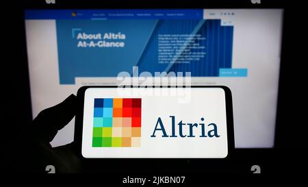 Personne tenant un smartphone avec le logo de la société américaine de tabac Altria Group Inc. À l'écran devant le site Web. Mise au point sur l'affichage du téléphone. Banque D'Images