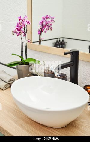 Lavabo élégant avec table de mixage noire sur comptoir lumineux dans la salle de bains moderne Banque D'Images