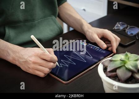 Homme utilisant une tablette numérique pour dessiner à la maison Banque D'Images