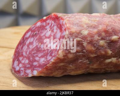 Un grand morceau de saucisse fumée sur une planche à découper en bois, photo macro. Banque D'Images