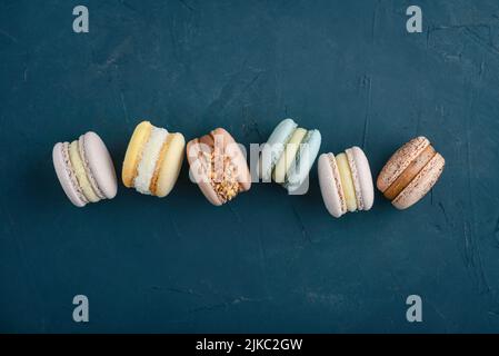 Macarons colorés sur fond bleu, vue du dessus Banque D'Images
