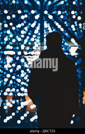 Une vue arrière d'un homme silhouette debout devant des reflets lumineux ronds Banque D'Images