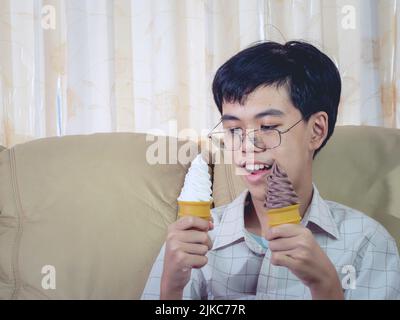 Un enfant d'Asie tient la glace à la vanille dans le cône de gaufres heureux souriant et manger délicieusement en été avec plaisir et bonne humeur. Banque D'Images