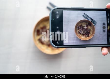 Shoot First Eat later concept, la prise de vue de dessus de pâtes à la sauce blanche aux truffes. Médias sociaux, partage de repas. Banque D'Images