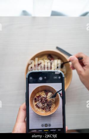 Shoot First Eat later concept, la prise de vue de dessus de pâtes à la sauce blanche aux truffes. Médias sociaux, partage de repas. Banque D'Images