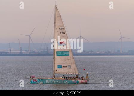 L'équipe des Bermudes yacht à l'aube au large de Southend Pier dans l'estuaire de la Tamise après avoir terminé la course de yacht Clipper Round the World. Parc éolien énergie éolienne Banque D'Images