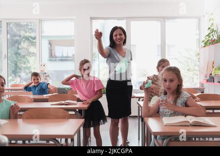 La fin de la pandémie. L'enseignant de l'école prend les masques protecteurs avec les élèves Banque D'Images