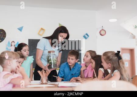 Enseignante avec des enfants en cours de biologie à l'école primaire menant des expériences scientifiques de biologie ou de botanique sur la croissance durable des plantes Banque D'Images