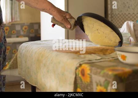 Une vieille grand-mère qui cuit de petites crêpes dans une casserole Banque D'Images
