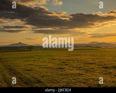 Coucher de soleil romantique sur un champ dans le nord de la Bohême. Le ciel est calme et avec peu de nuages et de soleil au-dessus de l'horizon. Banque D'Images