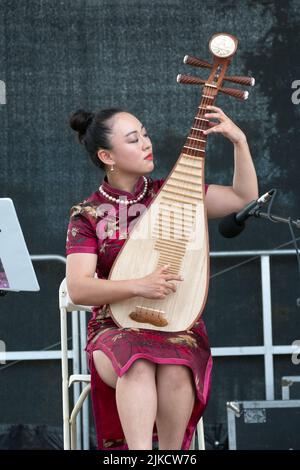 Un beau membre de l'ensemble de musique chinoise de New York joue la pipa, un instrument chinois traditionnel. Au Hong Kong Dragon Boat Fest Banque D'Images
