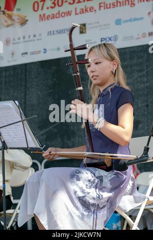 Un beau membre de l'ensemble de musique chinoise de New York joue l'erhu, un instrument chinois traditionnel. Au Hong Kong Dragon Boat Fest, New York Banque D'Images