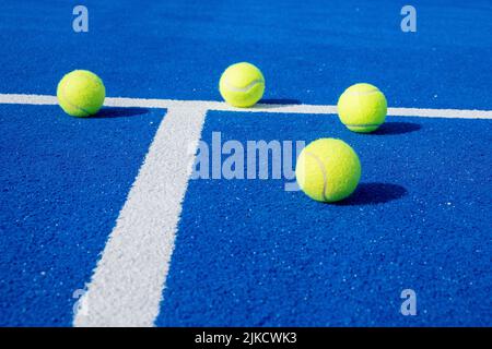 Mise au point sélective, quatre balles de paddle-tennis sur un court de paddle-tennis bleu. Sports de raquette Banque D'Images